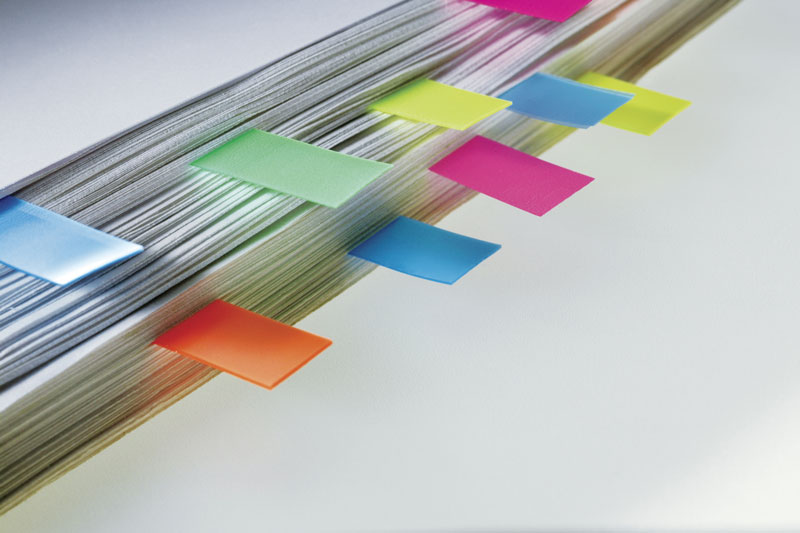 Stack of papers with color-coded flags color coding tabs in binder