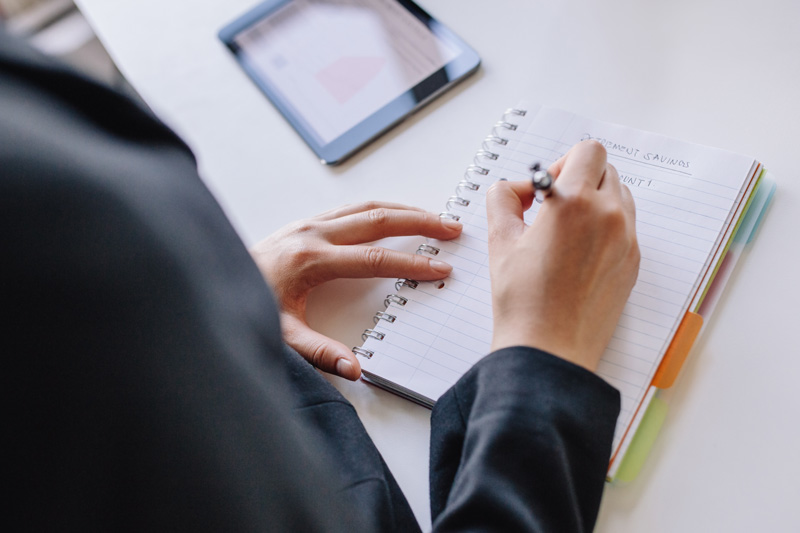 Businesswoman hands writing on notepad writing list in office
