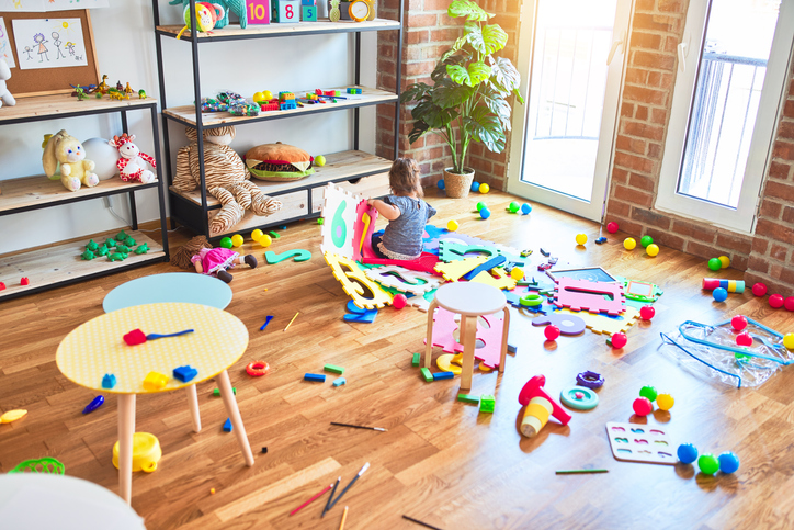 Beautiful toddler sitting on the floor playing with building blocks toy at kindergarten