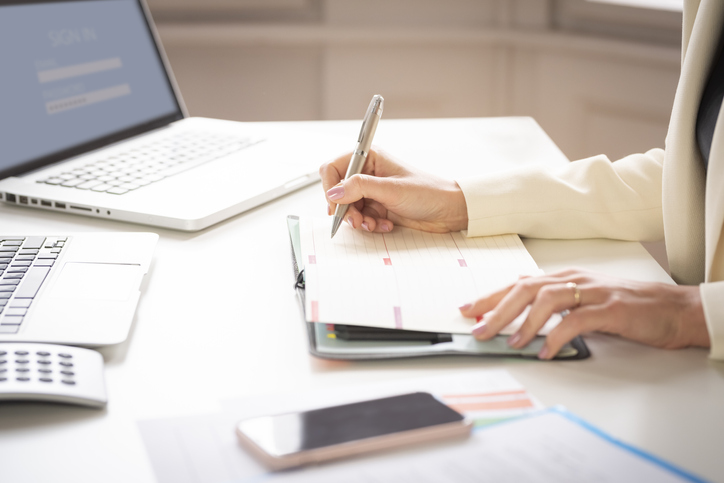 Close-up of businesswoman's hand while making note on the notebook