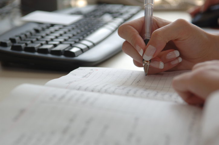 Busy businesswoman’s schedule Preparing for a zoom by by writing in agenda