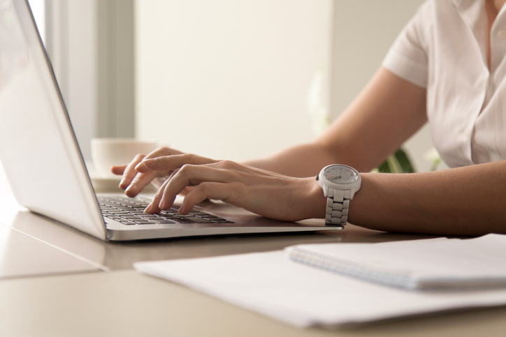 Womans hands typing on laptop at workplace Woman typing notes after zoom meeting