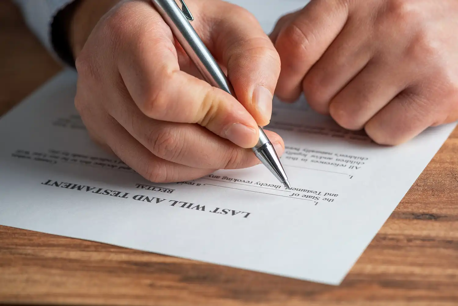 A hand with a pen filling out an Last Will